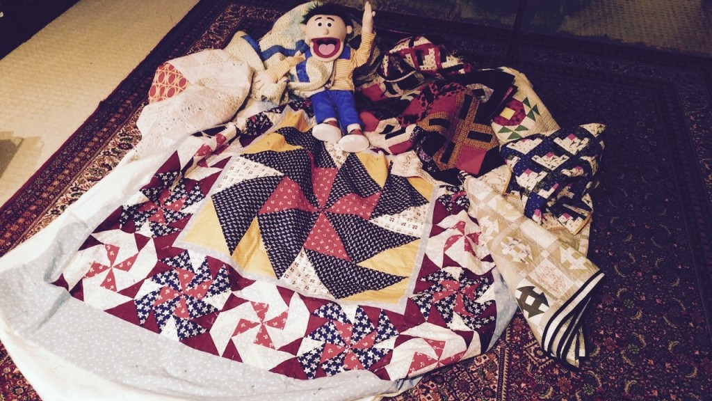 That's my puppet, Nathan, who is high-fiving life, sitting on the six quilts that have come home. Photo: Me